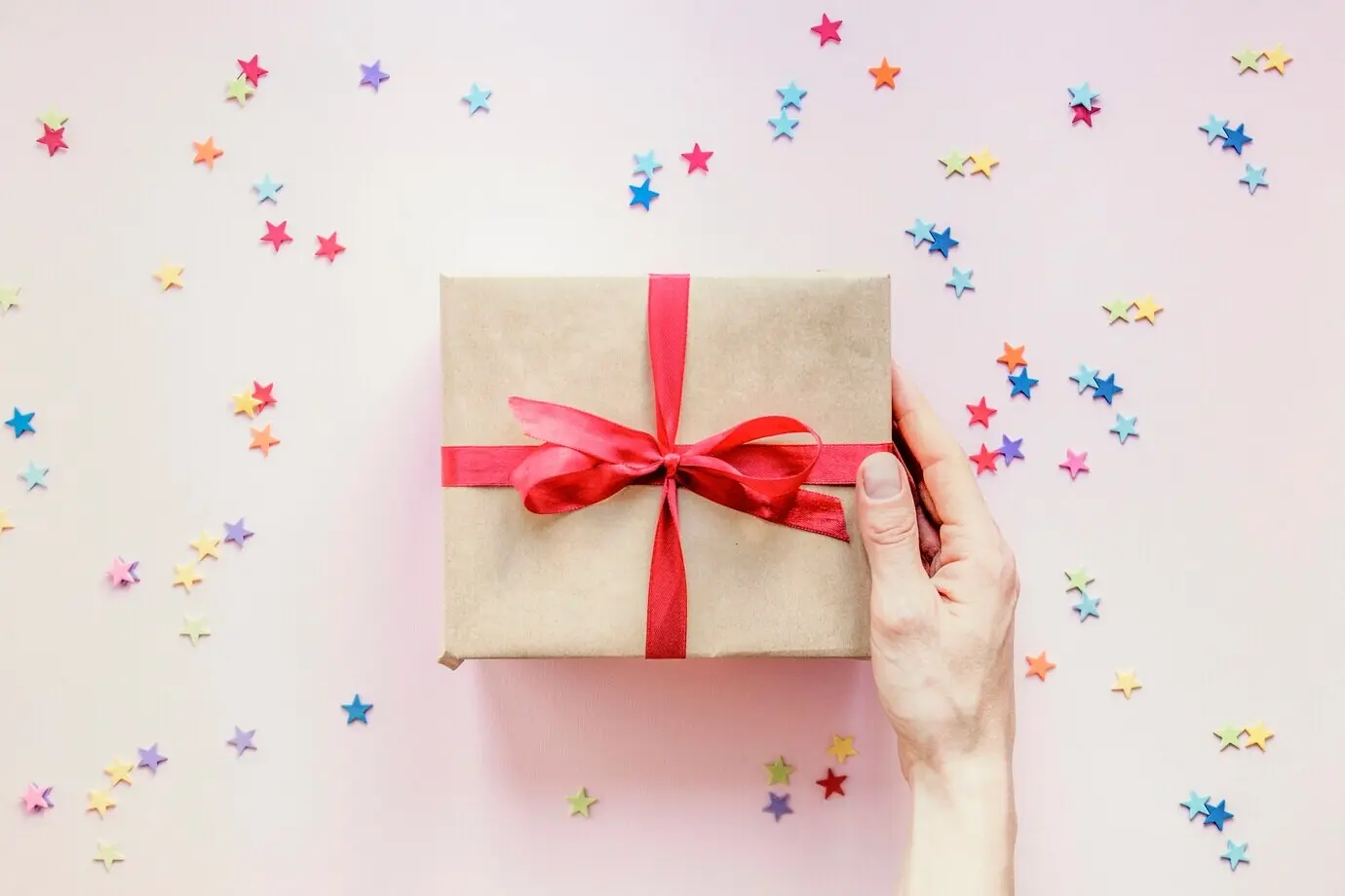 Angeschnittene Hand, die ein Geschenk hält.